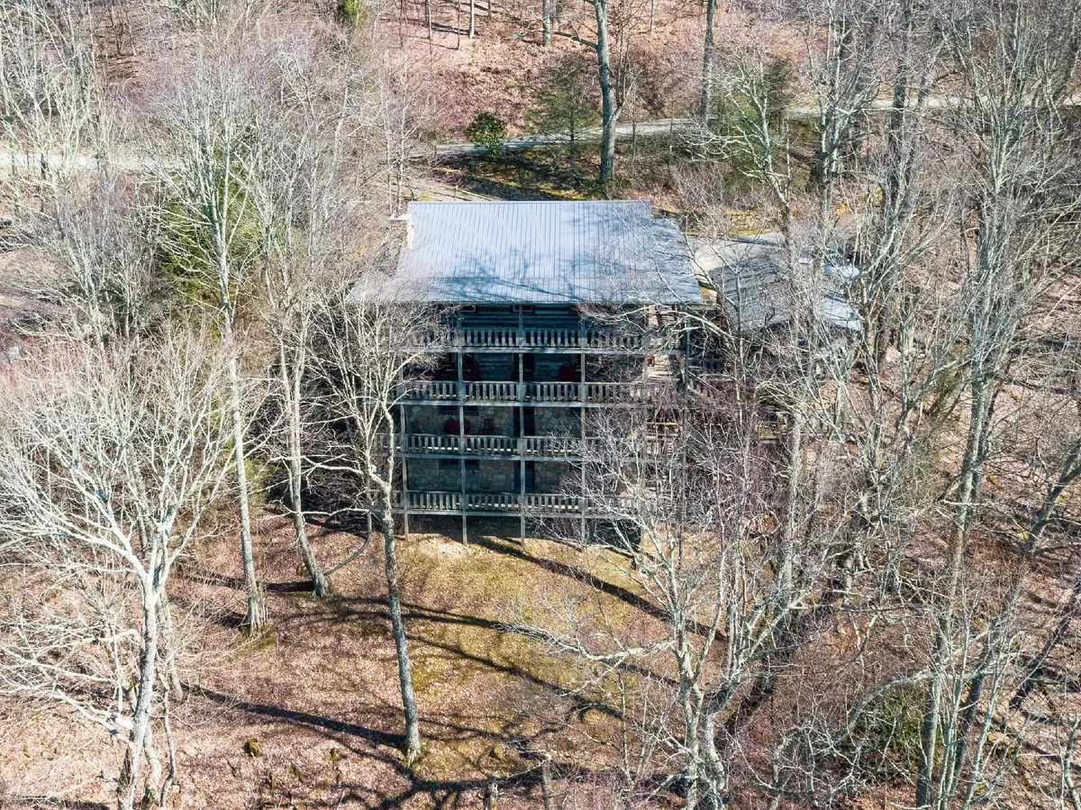 This image features the cabin's exterior surrounded by lush trees and open ground, showcasing the spacious private grounds and the building’s inviting structure. The outdoor setting emphasizes the tranquil and natural environment ideal for family gatherings and group retreats.